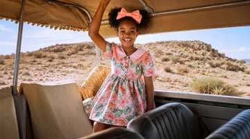 Luxury girls floral vacation dress in a safari jeep, lightweight designer travel outfit for family holidays, tropical print dress with pink collar and matching bow.