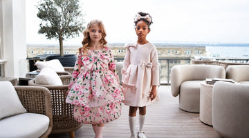 Girls in elegant floral and blush pink dresses, styled for chic family travel and special occasions.