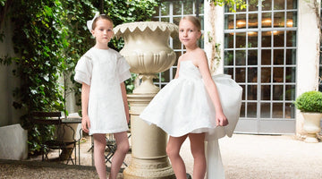 Elegant white girls dresses in garden courtyard with fountain backdrop