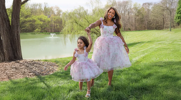 Elegant mother and daughter in matching couture dresses standing in a European villa garden with soft natural light.