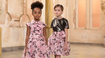 Two girls wearing elegant pink floral dresses from Mama Luma’s couture collection, featuring delicate 3D flower embroidery and satin details