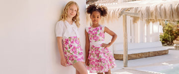 Luxury girls matching floral outfits in pink tones at a sunlit resort setting.