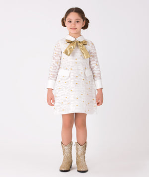  white long-sleeved dress adorned with daisy prints and accented with a shimmering gold bow on the front 