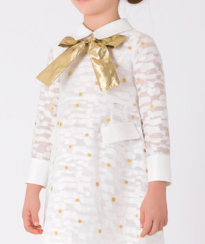 white long-sleeved dress with daisy prints and accented with a shimmering gold bow on the front 