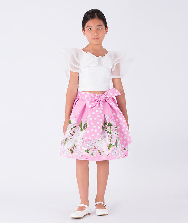white ruffled blouse and pink floral skirt with a polka dotted bow on the waist