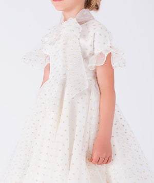charming organza dress adorned with ruffle details, shimmering golden polka dots, and a statement bow on the front