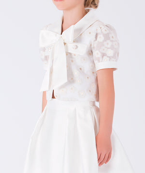 Classic white skirt and a puff-sleeve top adorned with a bow and daisies
