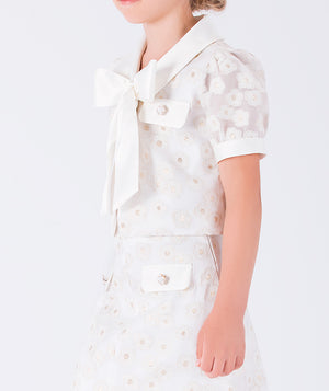a delicate jacket and a coordinating skirt, accented with a statement bow