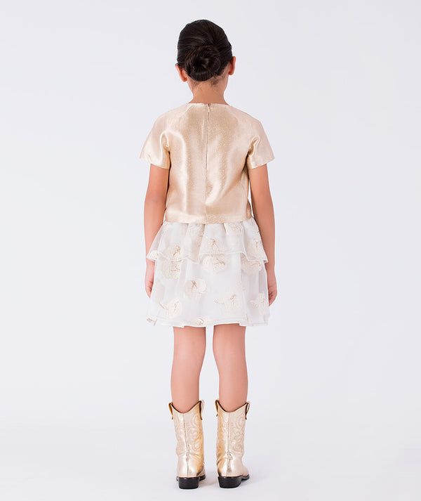 gold blouse paired with a layered ivory skirt