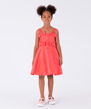 A sleeveless, vibrant coral A-line dress with chic bow details