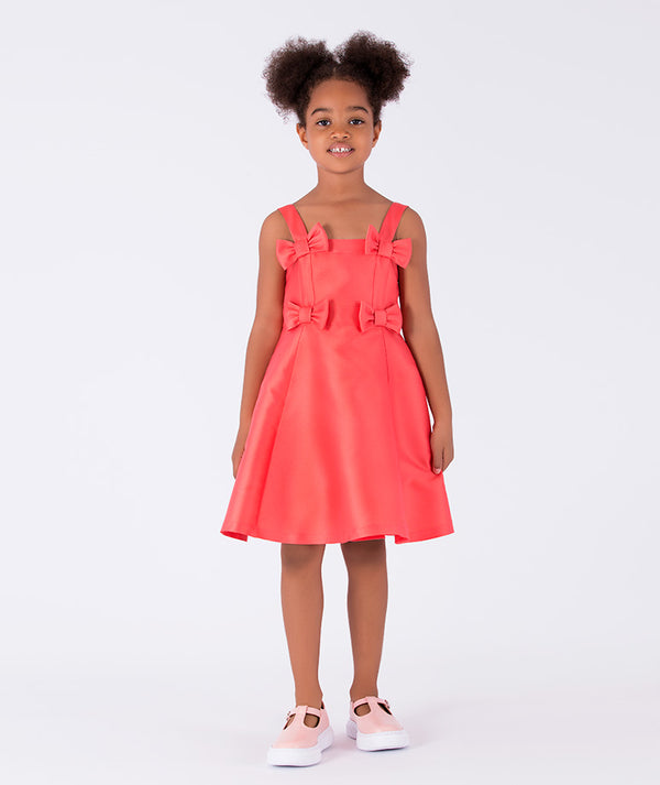 A sleeveless, vibrant coral A-line dress with chic bow details