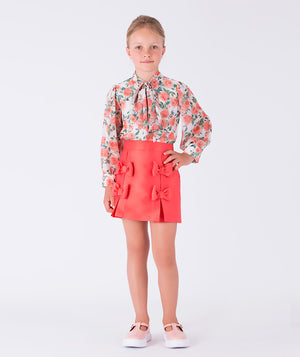 A floral-print blouse paired with a tailored coral skirt