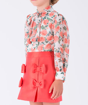 floral-print blouse paired with a tailored coral skirt