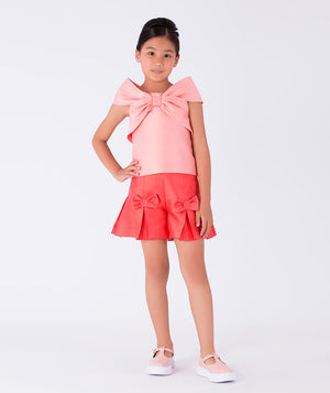 A cute pink bow top paired with a coral skirt with bow details