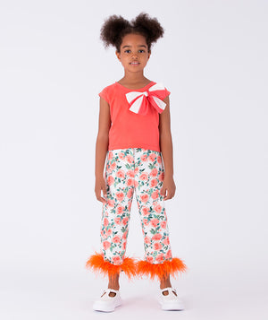 A vibrant coral top with a bow detail, paired with floral trousers featuring playful orange feather accents