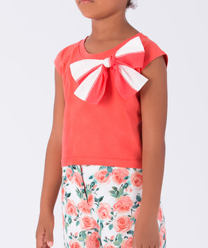 vibrant coral top with a bow, paired with floral trousers featuring playful orange feather accents