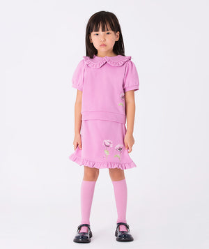 Lilac blouse with a ruffled Peter Pan collar and orchid print, paired with a lilac skirt featuring a ruffled hem and two orchid prints. A playful floral set.