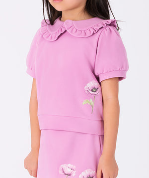 Lilac blouse with a ruffled Peter Pan collar and orchid print, paired with a lilac skirt featuring a ruffled hem and two orchid prints