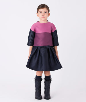 Mulberry blouse with navy sleeves, paired with a navy skirt finished with a subtle bow at the waist for a chic, balanced look.