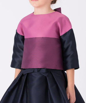 Mulberry blouse with navy sleeves, paired with a navy skirt finished with a subtle bow at the waist 