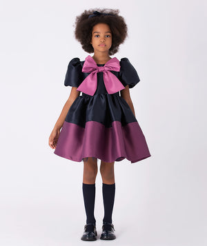 Navy dress featuring a playful puff skirt with a purple hem and a striking oversized mulberry bow on the front for a bold, stylish look.