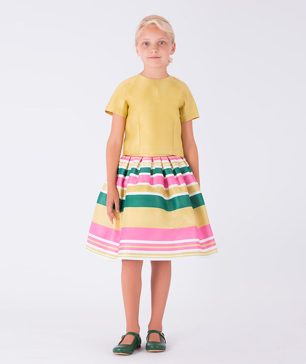A sunny yellow top paired with a joyful striped skirt