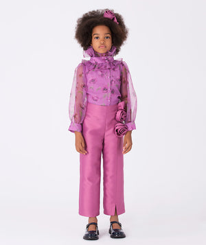 Lilac blouse with sheer sleeves and a high ruffled collar, paired with mulberry pants adorned with delicate 3D roses on the front. A whimsical floral ensemble.