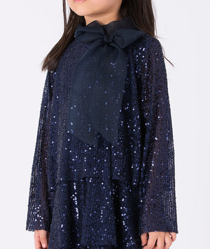 A navy glitter dress with long sleeves and a soft, sheer bow