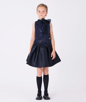 A sleeveless navy glitter blouse with an airy organza bow