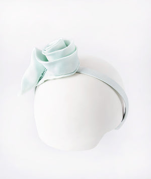 Aqua headband accented with a delicate 3D rose for a touch of sweet elegance.