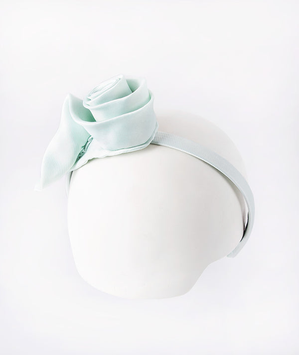 Aqua headband accented with a delicate 3D rose for a touch of sweet elegance.