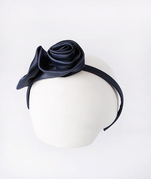 Navy headband accented with a delicate 3D rose for a touch of sweet elegance.