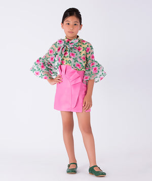A vibrant floral blouse with dramatic bell sleeves, paired with a pink ruffled skirt