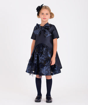  an elegant navy blue blouse with a large bow and floral textured skirt