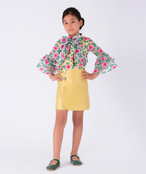 a bold floral blouse with bell sleeves, styled with a minimal yellow skirt