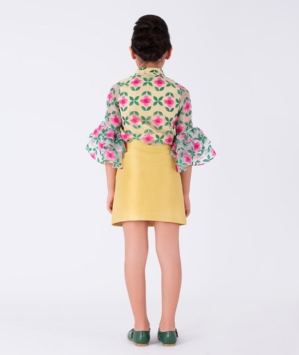 a bold floral blouse with bell sleeves, styled with a yellow skirt