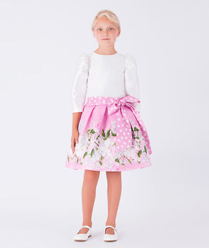 satin balloon sleeve white blouse with pink floral skirt that has a big polka dotted bow on the waist
