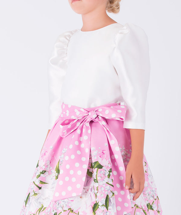 white long balloon sleeved blouse with a pink floral skirt that has a polka dotted bow 