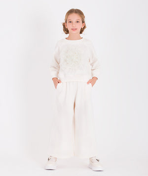 a white tracksuit with a large 3D flower applique