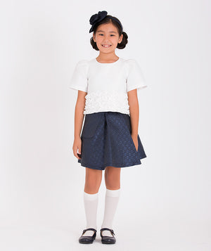 a stylish white top with floral texture and navy A-line skirt