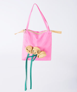 A charming designer pink handbag with delicate white yellow and flowing green ribbons