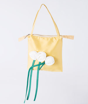 A charming designer yellow handbag with delicate white roses and flowing green ribbons