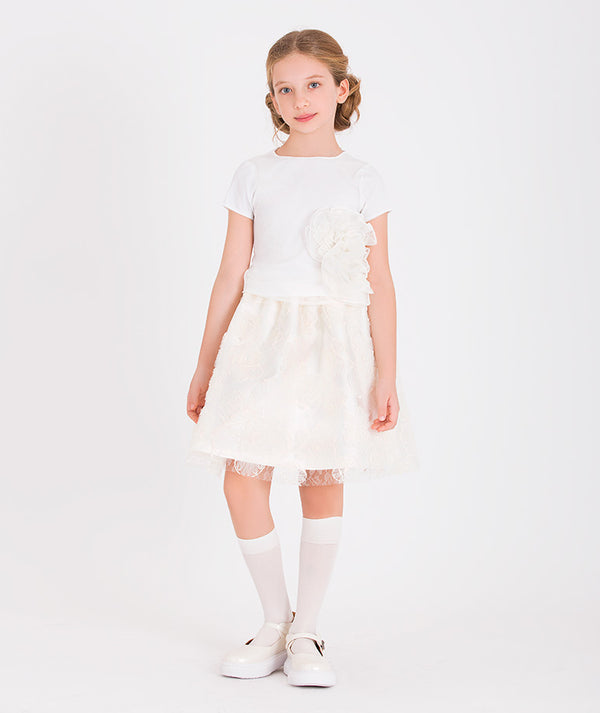 a white short-sleeve top with a large floral applique paired with a lace skirt