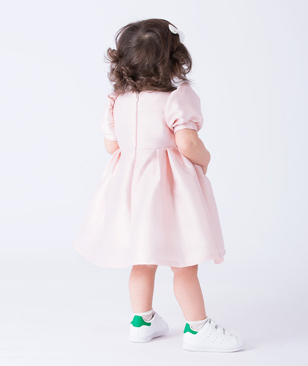 Adorable puff-sleeve baby dress crafted from soft satin with jeweled buttons and pleated detailing. 
