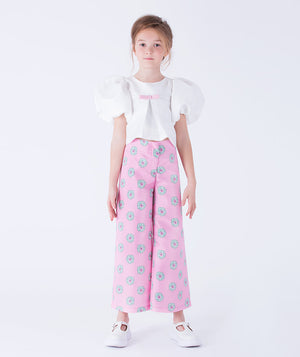elegant white puff-sleeve blouse, adorned with a delicate pink bow, perfectly complemented by wide-leg pink pants featuring playful floral motifs