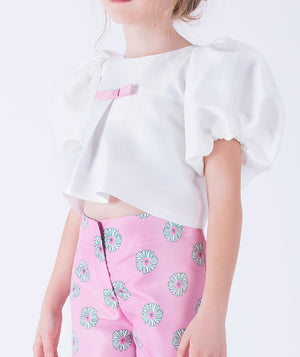 elegant white puff-sleeve blouse with a delicate pink bow and wide-leg pink pants featuring playful floral motifs