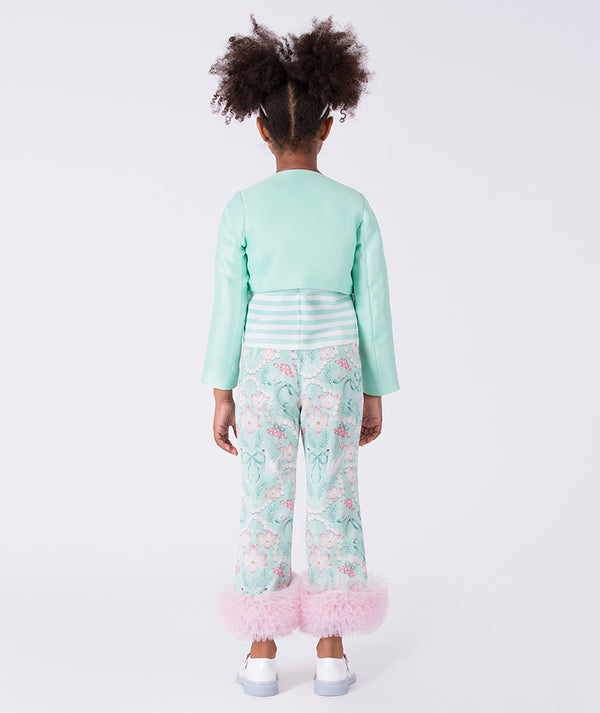 Child wearing a light green outfit with floral pants on a white background