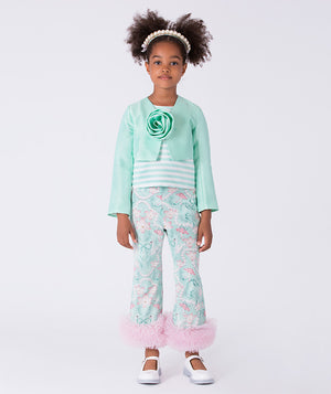 Young girl wearing a mint green outfit with floral pants on a white background