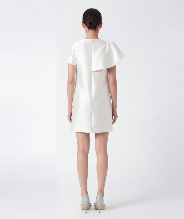 Woman wearing a white dress with a ruffled collar on a white background