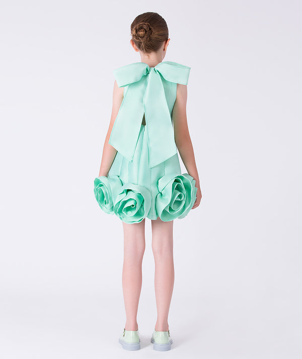 Mint green dress with floral details and a large bow on a white background